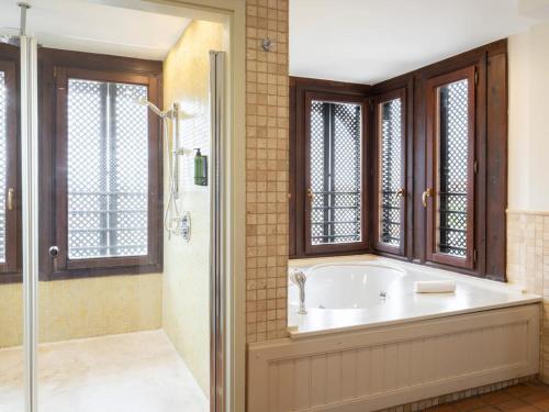 a bathroom with a tub and a shower with windows at Ona Mar Menor Golf & Spa in Torre-Pacheco