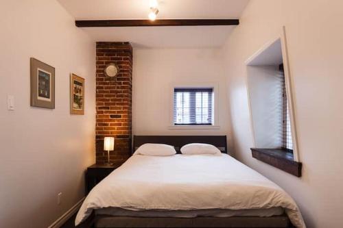 a bedroom with a bed and a brick wall at Comfort & Getaway in Old Levis - Studio Urbain in Lévis