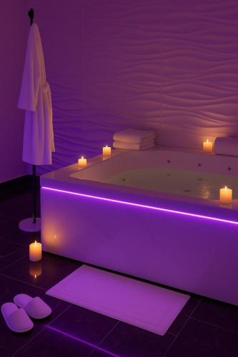 a purple bathroom with a tub with candles and lights at Suite Dima in Vedène