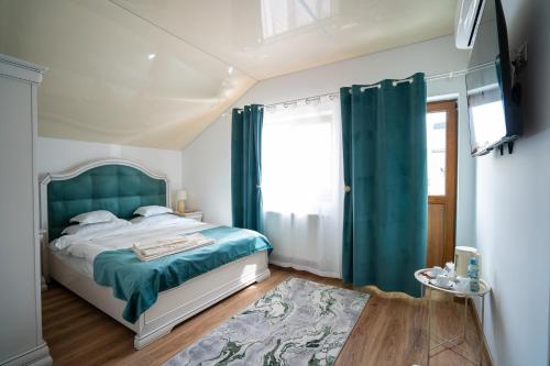 a bedroom with a bed with a green headboard and a window at Serafim's Suites Airport in Iaşi