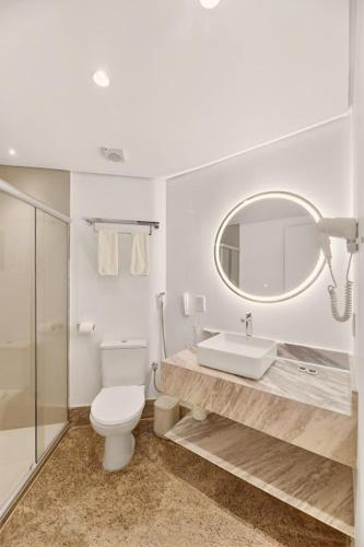 a bathroom with a toilet and a sink and a mirror at Hotel Brisa Tower Maceió in Maceió