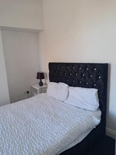 a bedroom with a white bed with a black headboard at Waterloo apartment in Middlesbrough