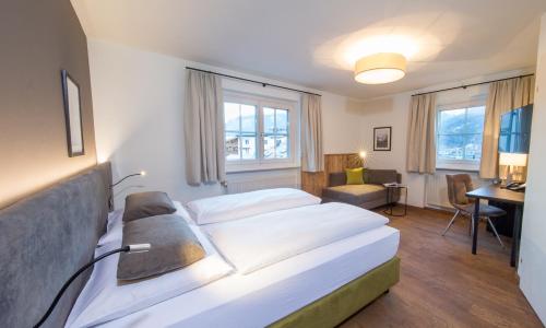 ツェル・アム・ゼーにあるHEITZMANN - Hotel & Rooftopのベッドとデスクが備わるホテルルームです。