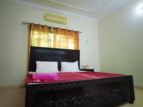 a bedroom with a black bed with a red bedspread at Satti Palace Guest House in Rawalpindi