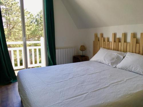 a bedroom with a white bed and a large window at Villa Myriam in Deauville