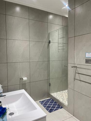 a bathroom with a shower and a sink at Utopia Guest House in Alberton