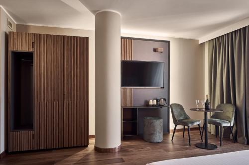 a hotel room with a bed and a table and a tv at Hotel Kristal Palace - Tonelli Hotels - Adult Friendly in Riva del Garda
