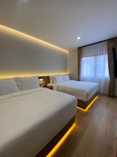 a hotel room with two beds and a window at Blissful Homestay Batam in Nagoya