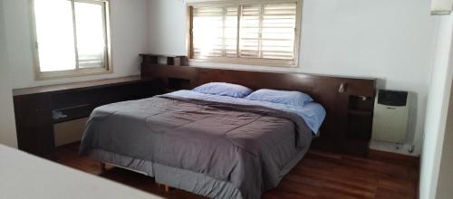 a bedroom with a bed with a wooden headboard and two windows at Casa 51 La Plata in La Plata