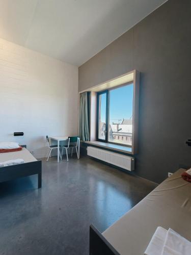 a room with a large window and a table and chairs at Hostel Groeninghe in Kortrijk