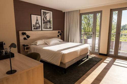 a bedroom with a large bed and a balcony at Le Relais de La Malmaison, a member of Radisson Individuals in Rueil-Malmaison