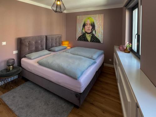 a bedroom with a large bed with a painting on the wall at Louise Boutique Apartment 3 in Friedrichshafen
