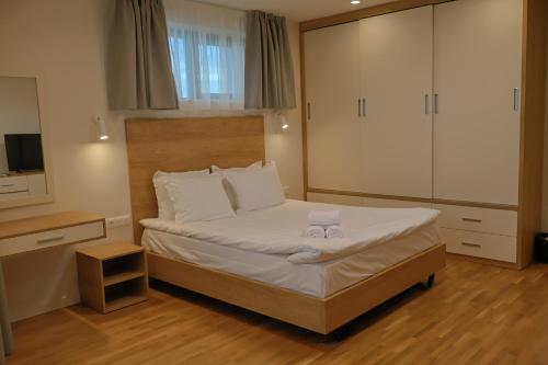 a bedroom with a bed with white sheets and a television at Complex SamElyon Residence in Samokov