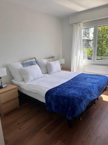 a bedroom with a large bed with a blue blanket at Appartement 2 chambres avec balcon terrasse in Villars-sur-Glâne