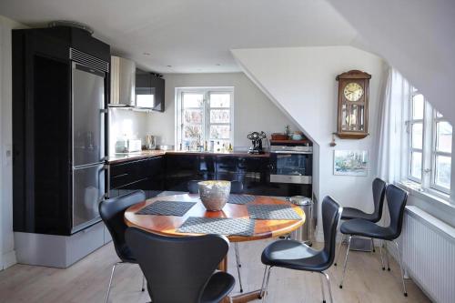 a kitchen with a table and chairs and a clock at Spacious House In Skagen in Skagen