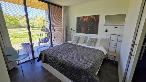 a bedroom with a bed and a large window at Sfeervol chalet midden in de natuur in Halle