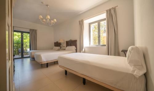 a bedroom with two beds and a chandelier at Hotel Villa Marcilla by Pandora Hoteles in Marcilla