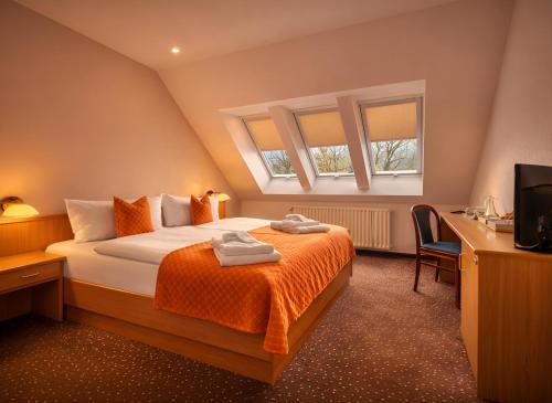 a bedroom with a bed with orange sheets and two windows at Lázeňský hotel Pyramida in Františkovy Lázně