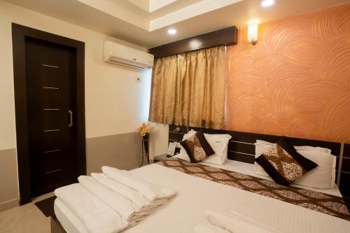 a bedroom with a bed with white sheets and pillows at Hotel Shree Vatika in Bhopal