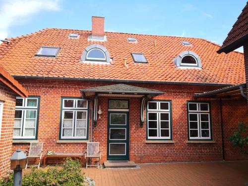 a red brick house with two chairs and a door at Haus Thulboden in Heiligenhafen