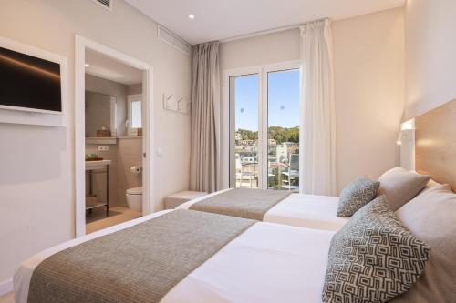 zwei Betten in einem Hotelzimmer mit Fenster in der Unterkunft Hotel Eden Soller in Port de Sóller