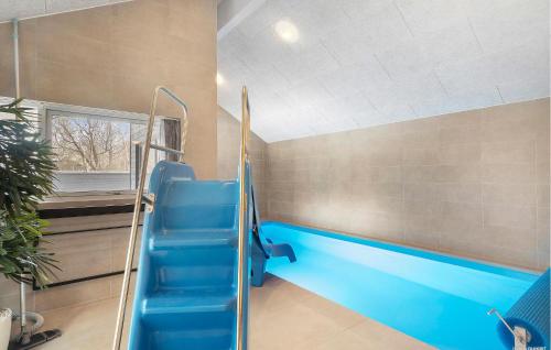 a swimming pool in a room with a blue slide at Beautiful Home In Ringkøbing With Sauna in Ringkøbing