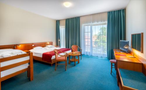 a hotel room with two beds and a television at Hunguest Hotel Aqua Sol in Hajdúszoboszló
