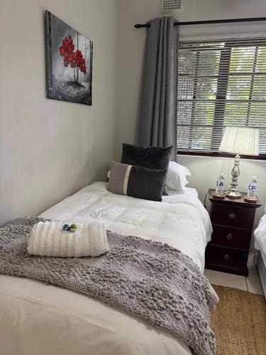 a bedroom with a bed with a blanket and a window at Tranquil Gardens in Pietermaritzburg