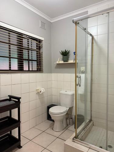 a bathroom with a toilet and a glass shower at Tranquil Gardens in Pietermaritzburg