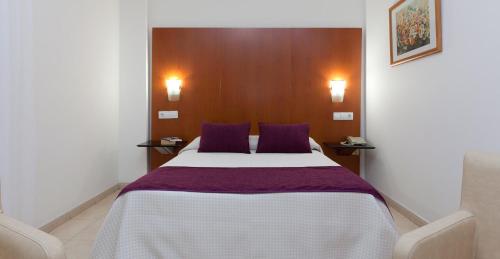 a bedroom with a large bed with purple pillows at Hotel Verol in Las Palmas de Gran Canaria
