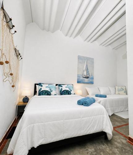 a white bedroom with two beds and a couch at Casa Vacacional Playa del Sur in Chichiriviche