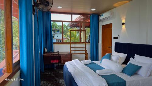 a bedroom with a bed with blue curtains and a window at Nature View Villa in Badulla