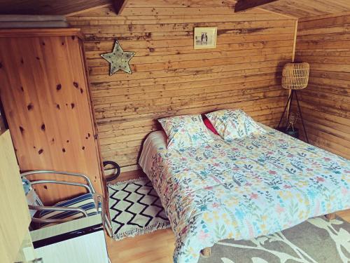 a bedroom with a bed in a wooden wall at Chalet dans notre jardin in Parigné