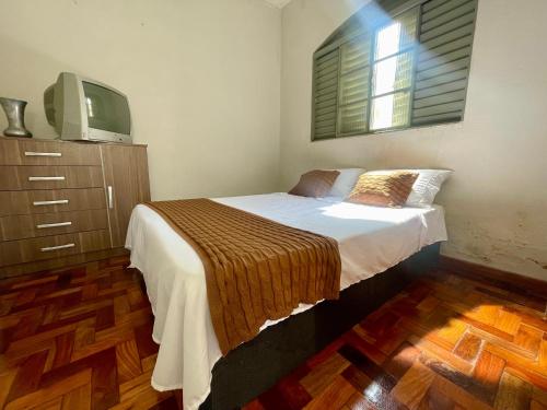 a bedroom with a bed and a tv on a dresser at Casa Jardim Centro in Patos de Minas