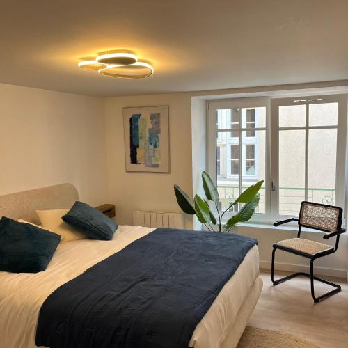 a bedroom with a large bed and a chair at Les Appartements de Millau in Millau