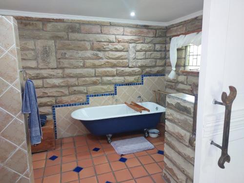 a bathroom with a stone wall and a bath tub at Ben Nevis Guest House in Clocolan