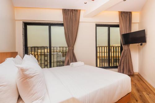 a bedroom with a white bed and two windows at RaRa Residence in Mumbai