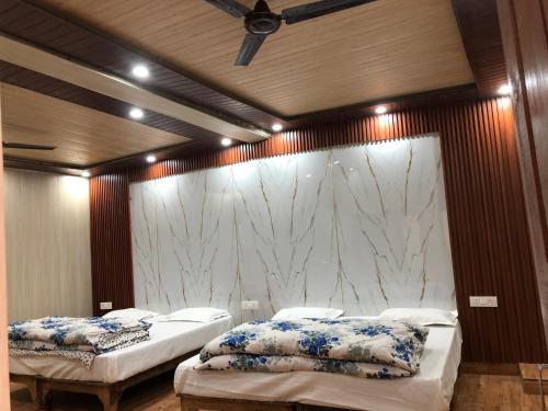 two beds in a room with a marble wall at Hotel Him darshan in Madheso
