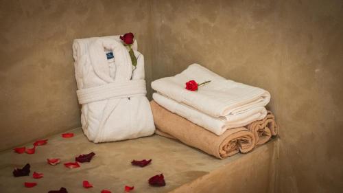 a pile of towels sitting on a counter with roses at Igrane House - Resort & Spa in Aït Faska