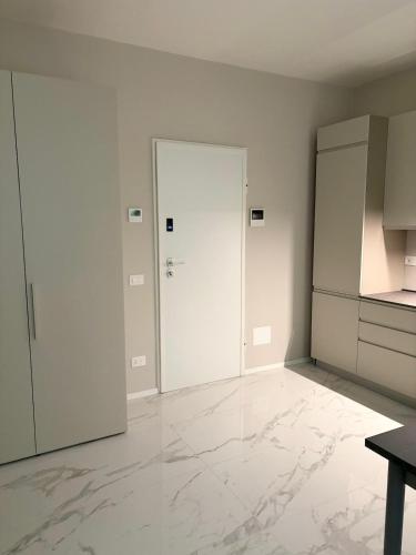a white room with a door and a kitchen at Aura Suite in Parma