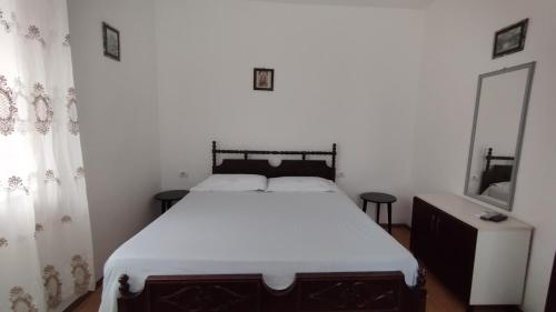een slaapkamer met een groot bed met witte lakens bij Lili's House in Delvinë