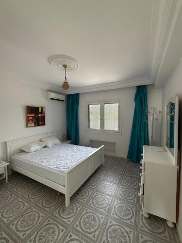 a bedroom with a white bed and blue curtains at Duplex Marina Monastir in Monastir