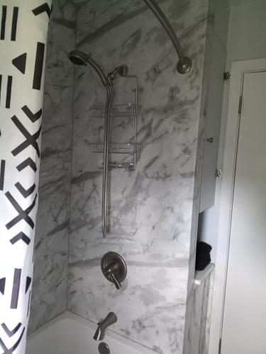 a shower in a bathroom with a marble wall at Binghamton Studio in Binghamton
