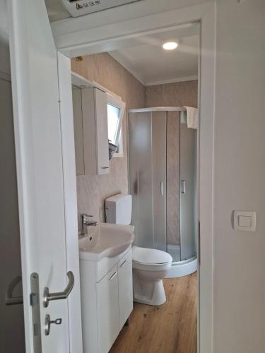a white bathroom with a toilet and a sink at Camp Phoenix in Srima