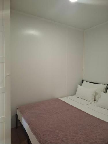 a bedroom with a bed with white walls at Camp Phoenix in Srima