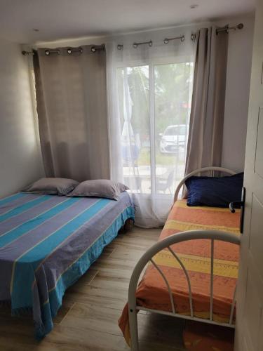 a bedroom with two beds and a window at Hibiscus holiday in Capesterre-Belle-Eau