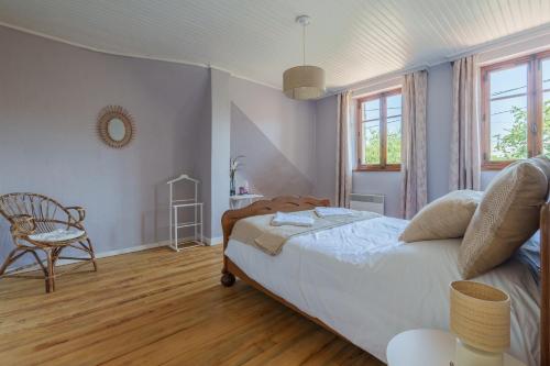 a bedroom with a bed and a chair and windows at Maison T2 - Le Boichot in Dole