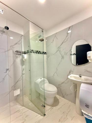 a bathroom with a toilet and a glass shower at Hotel Confort Ariari in Granada
