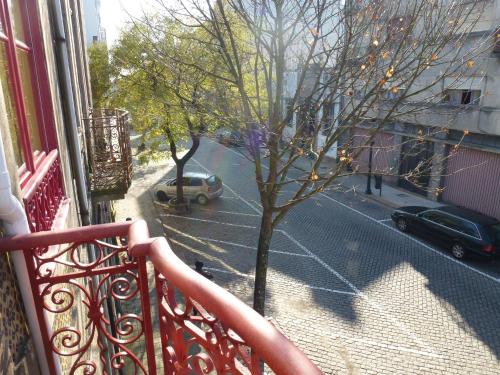 a balcony with a tree and a street with a car at Canvas Atelier Hostel in Porto