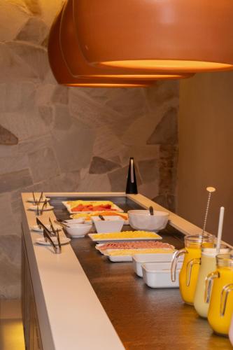a buffet line with plates of food on a counter at Kennedy Slim Hotel in São José